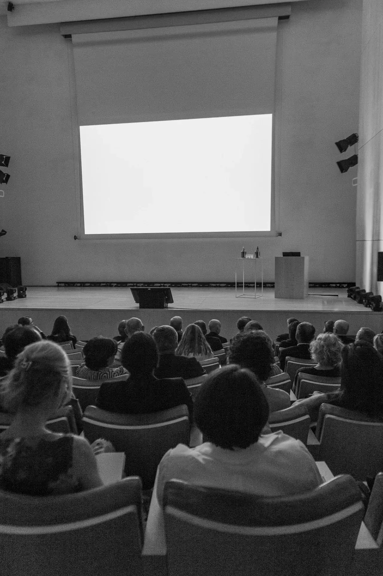 Platea e palco di una conferenza, fotografati in bianco e nero da FotoGiove