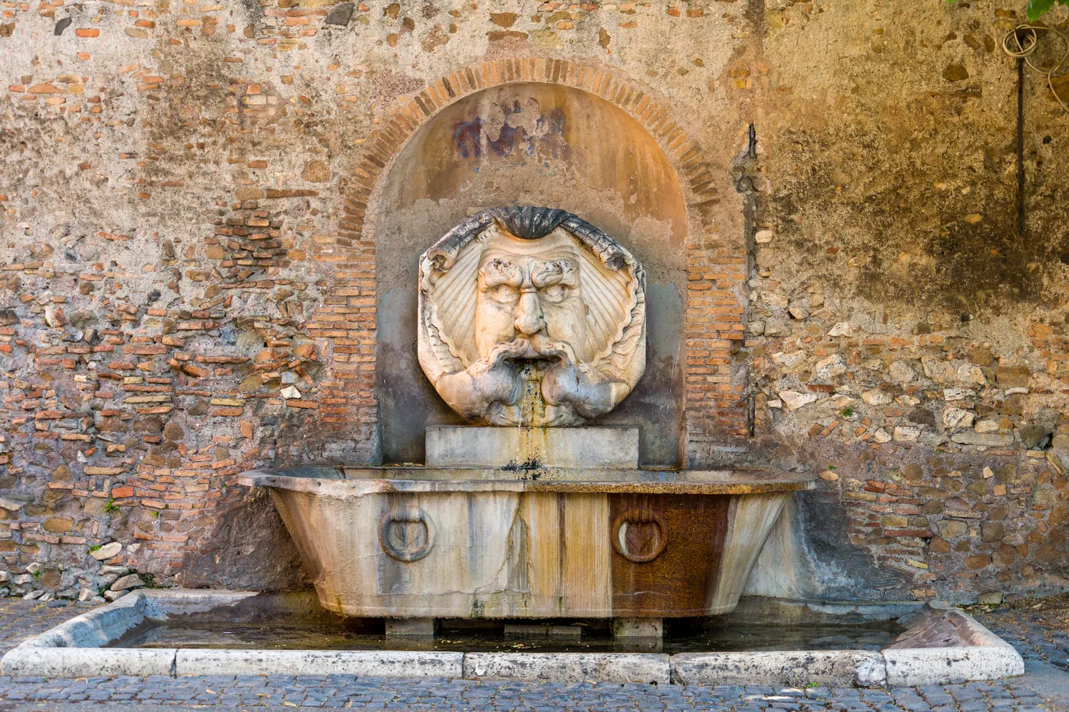 Fontana con mascherone in pietra e bacino rettangolare a Roma