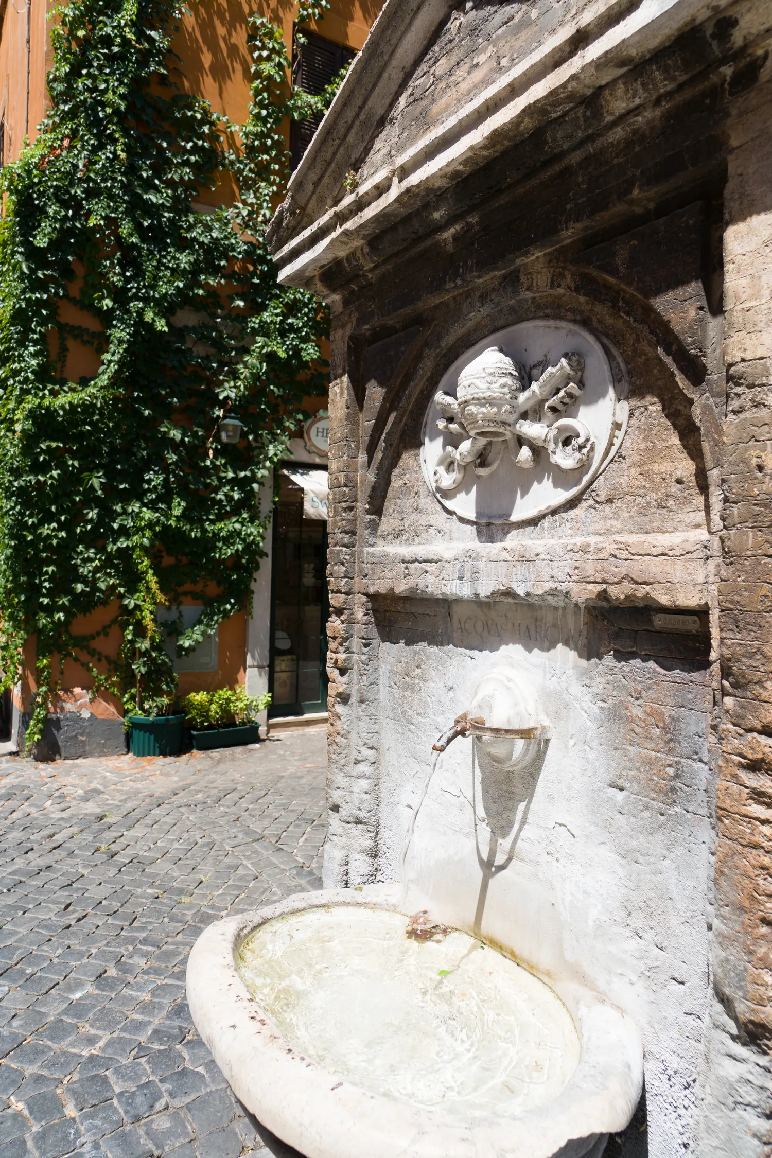 Piccola fontana in travertino con acqua corrente e muro in mattoni