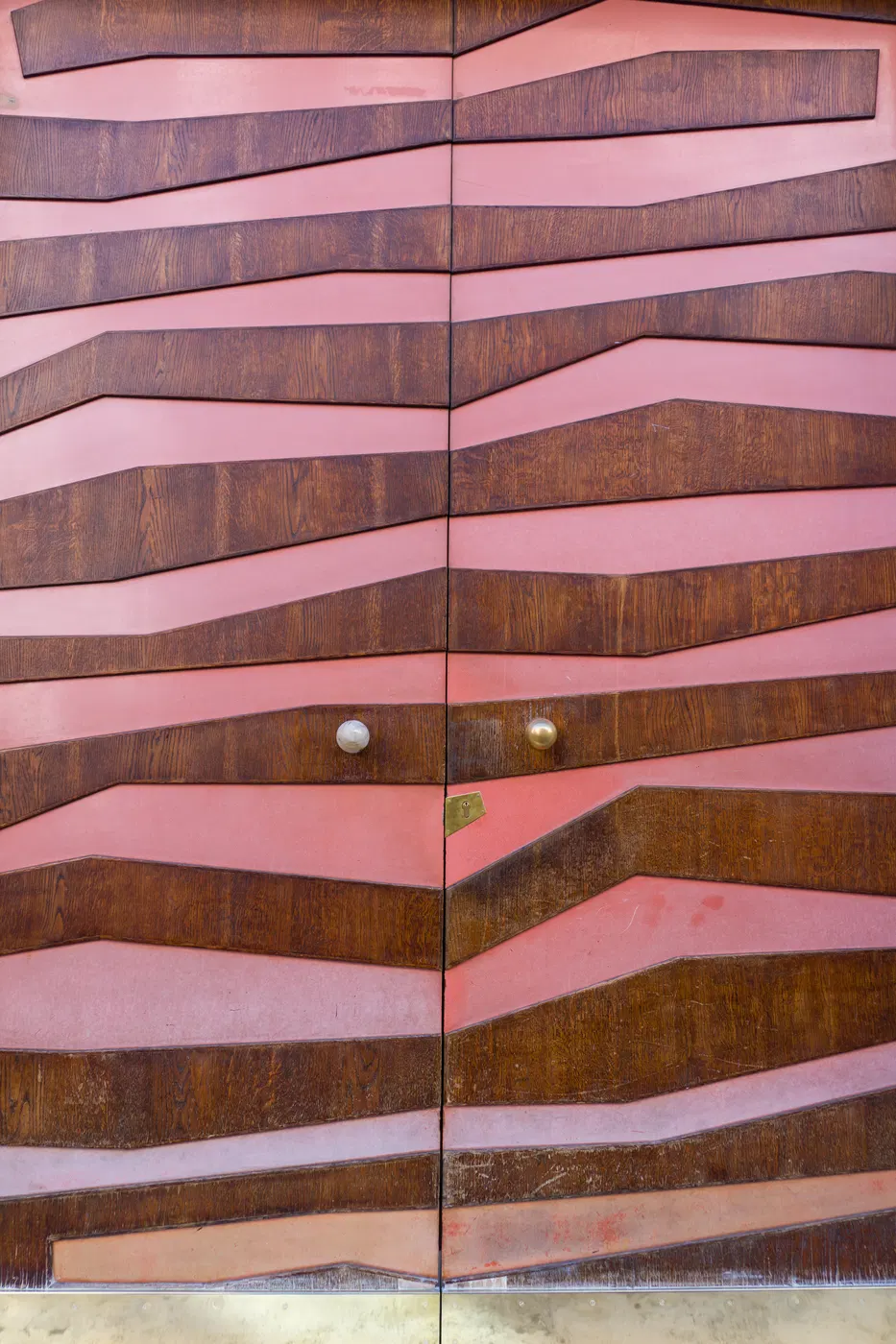 Portone con geometrie lignee e parete rosa