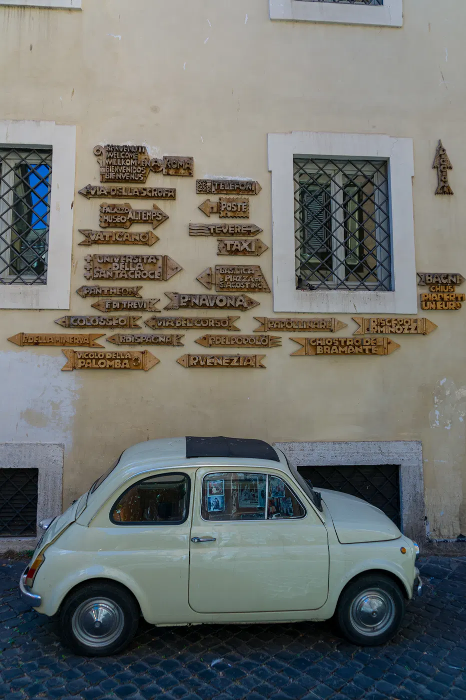 Targhe e insegne su muro di Roma, con automobile d’epoca