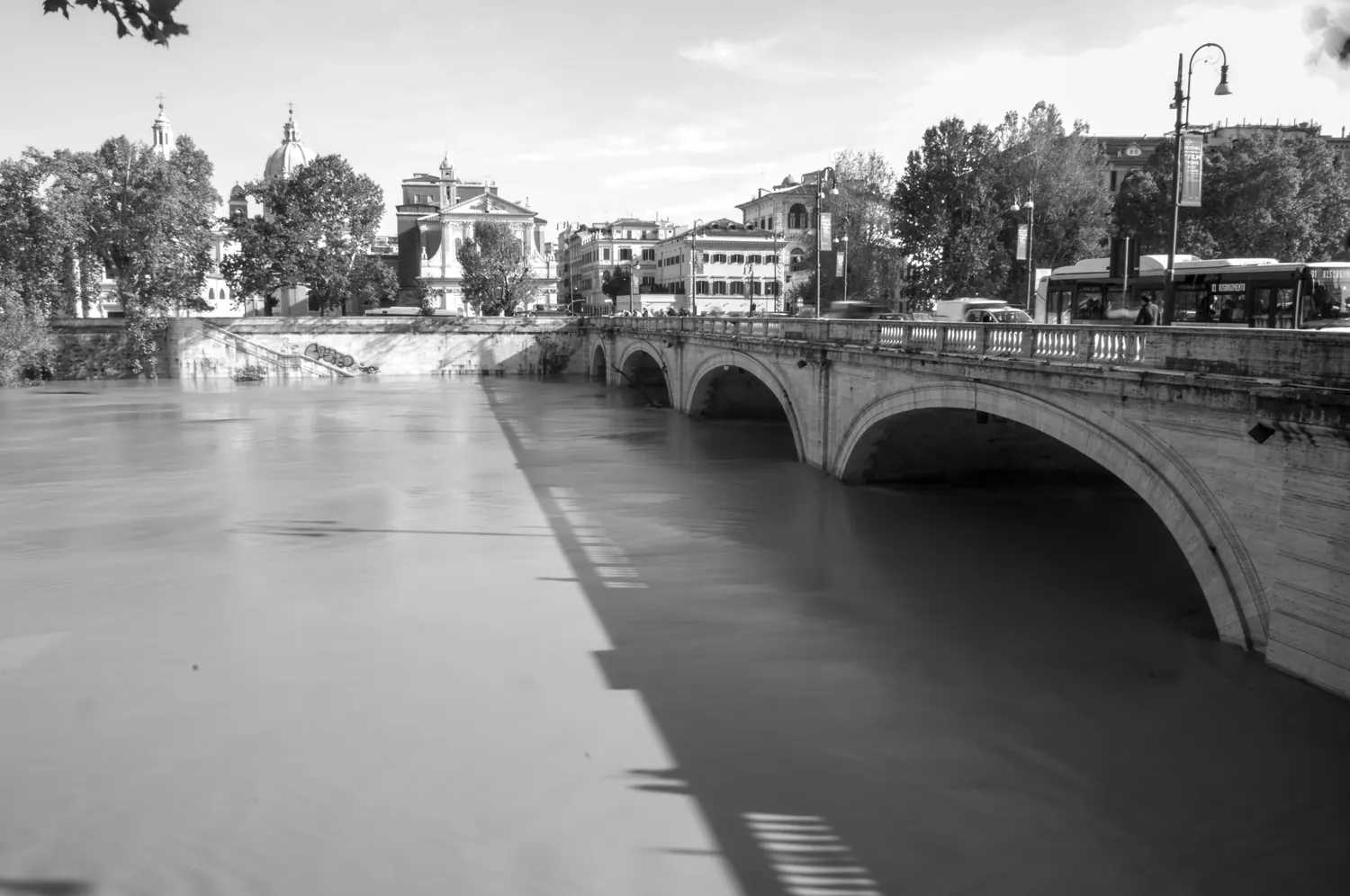 Ponte sul Tevere fotografato in bianco e nero dalla sponda del fiume