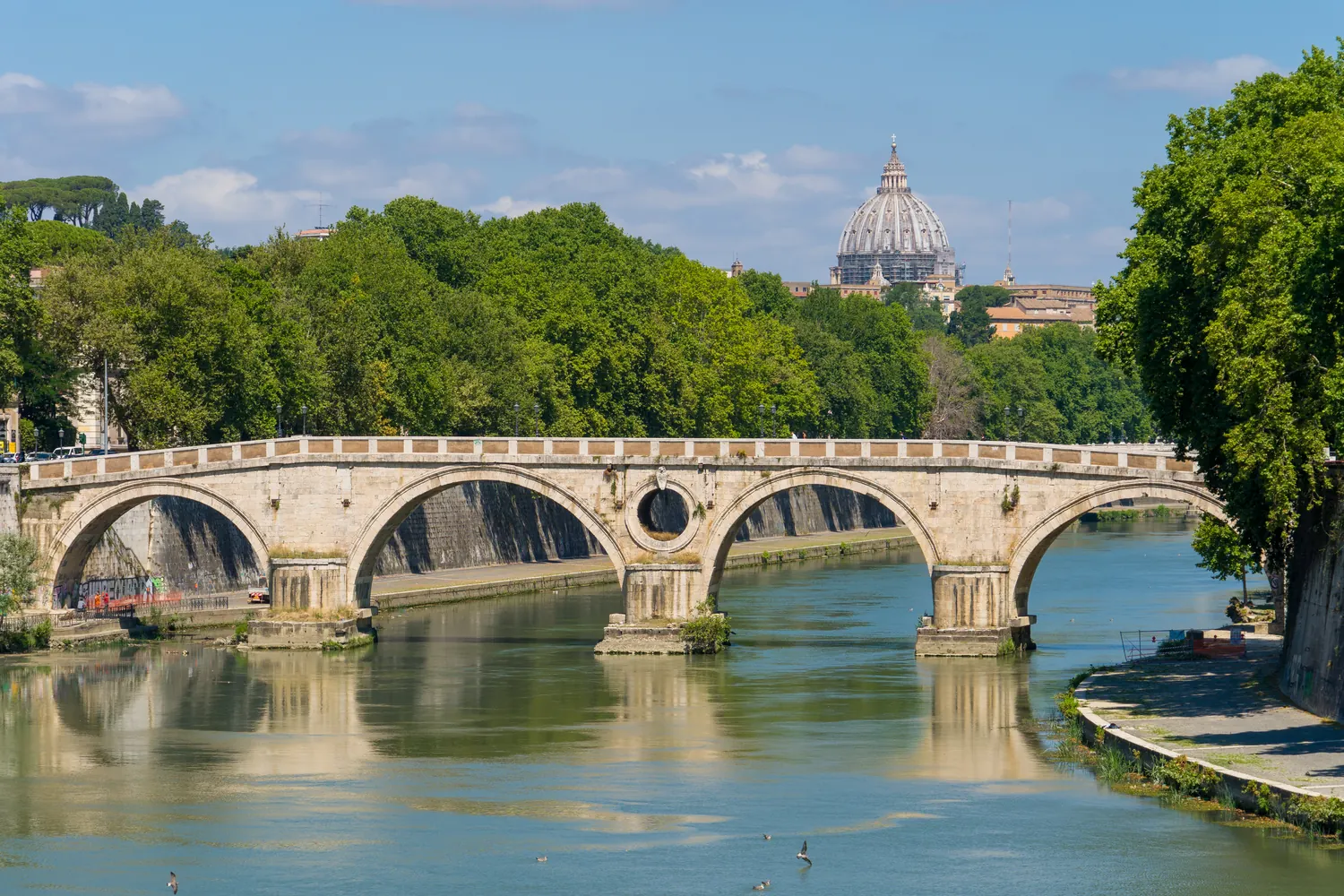 Ponte storico sul Tevere con cupola di San Pietro in lontananza
