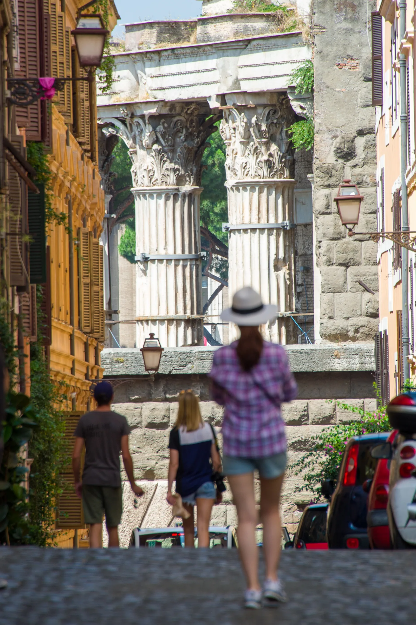 Colonne antiche fotografate attraverso un vicolo del Rione Monti con passanti
