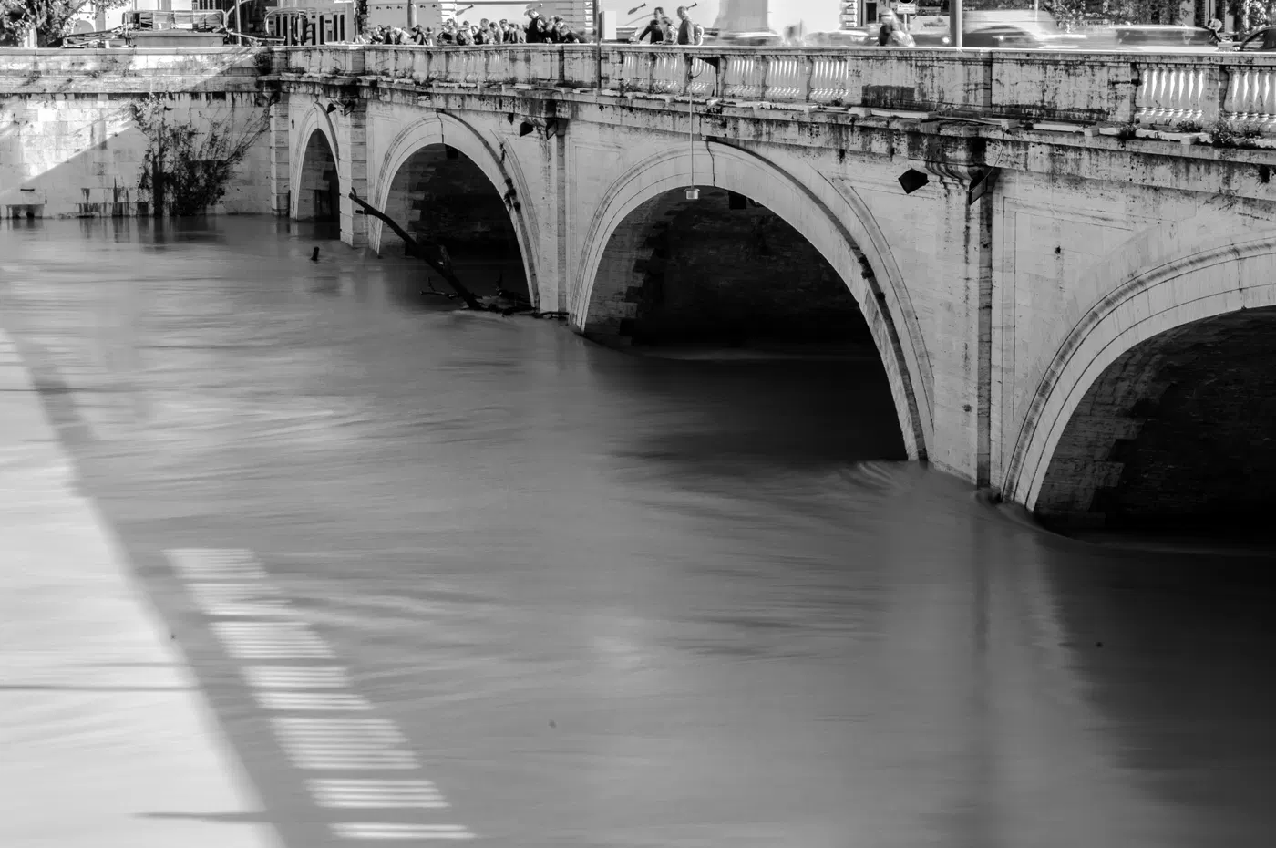 Arcate di un ponte sul Tevere con acqua e ombre, fotografia in bianco e nero