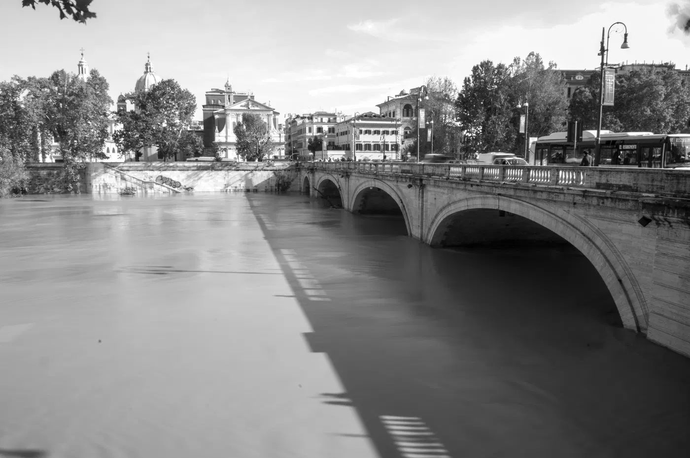 Ponte sul Tevere con riflessi e gradini delle rive, fotografia d’archivio in bianco e nero