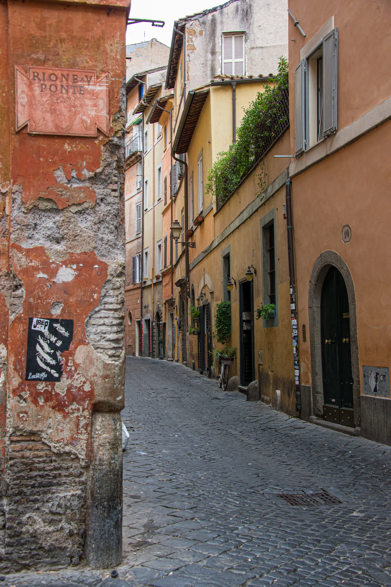 Stradina di Trastevere con sampietrini, muri color ocra e prospettiva stretta