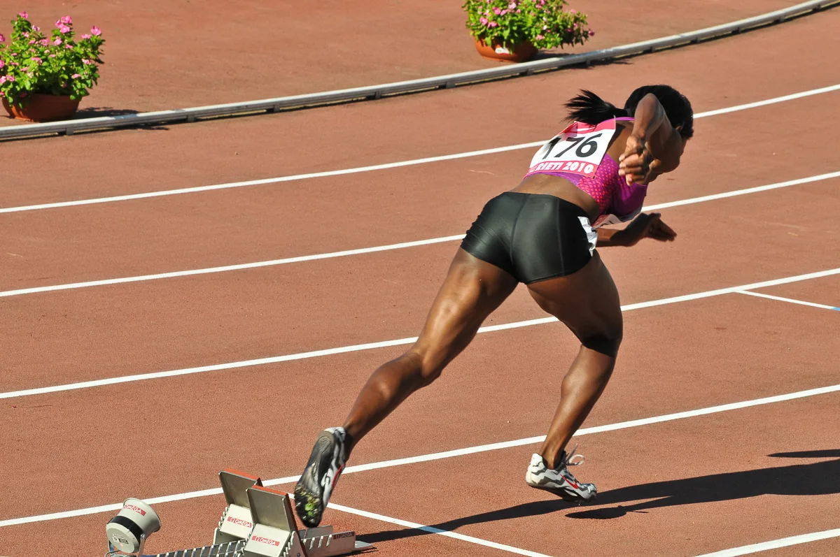 Sprinter in uscita dai blocchi di partenza durante una gara di atletica