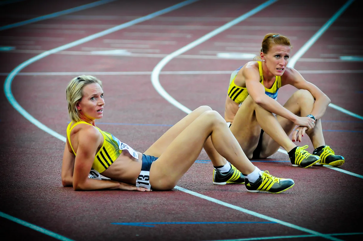 Due atlete sedute sulla pista al termine della gara