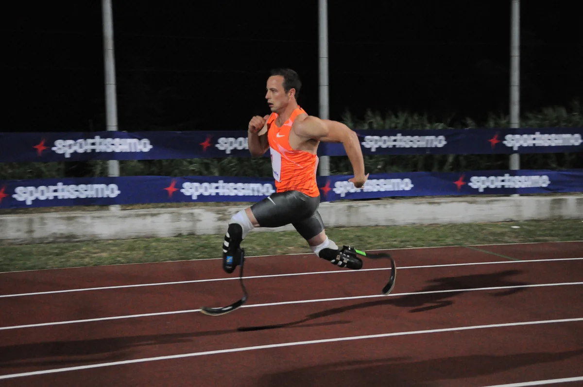 Atleta paralimpico in corsa sulla pista durante una gara serale