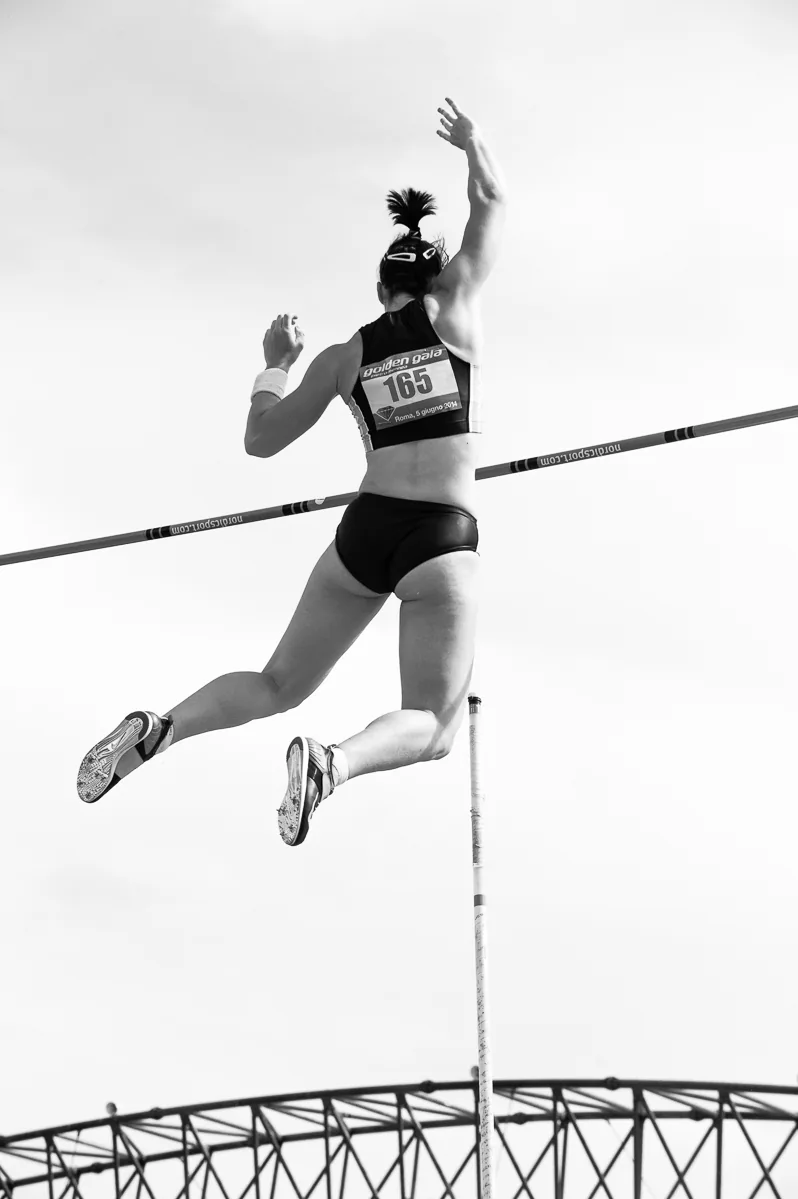 Atleta durante un salto con l’asta fotografato in bianco e nero